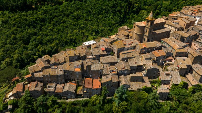 Vista aerea del centro storico di Capranica, con case in pietra dai tetti rossi e la Chiesa di San Giovanni.