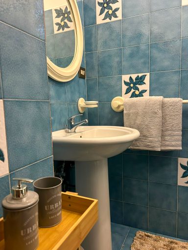 Lavabo con specchio rotondo, asciugamani piegati e dispenser per sapone.