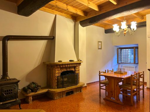 Sala rustica luminosa con camino. Ampia sala con camino, stufa a legna, tavolo in legno per otto persone e finestra.