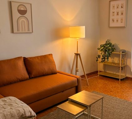Atmosfera serena – Casa Van Lente Angolo relax con divano arancione, luce calda e decorazioni minimal.