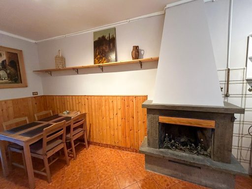 Zona pranzo accogliente con tavolo in legno e camino in pietra.