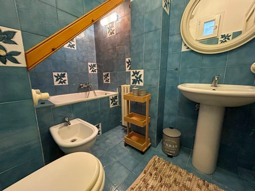 Bagno con piastrelle blu, lavabo, bidet, WC, vasca da bagno e doccia.