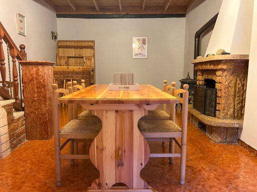 Accogliente sala da pranzo con camino al piano inferiore Tavolo in legno con sedie, camino e arredamento rustico nel piano inferiore dell’alloggio Casa Van Lente
