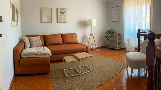 Soggiorno luminoso – Casa Van Lente Ingresso del soggiorno con divano arancione, tavolini moderni e luce naturale.